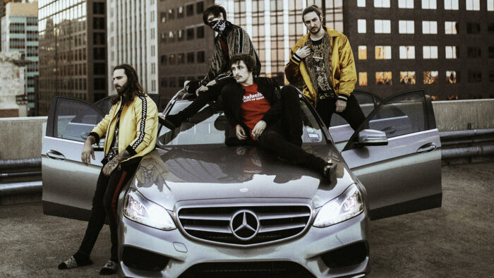 The band Polyphia sat upon a Mercedes car